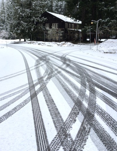 Tire tracks crisscross on a snowy road.