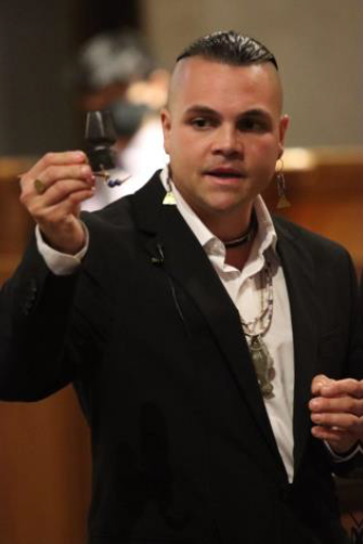 Drew Shuptar-Rayv in a blue blazar and white shirt holding a small object in his hand