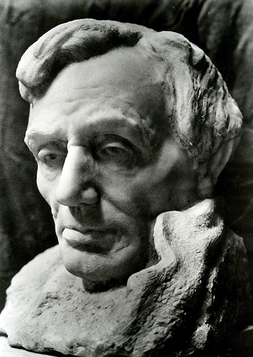 Bust of Abraham Lincoln, carved from marble by Gutzon Borglum in 1908.  Lincoln is portrayed looking towards the left, with wavy hair and part of a collar next to the left side of his jaw.