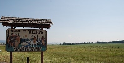 Wooden sign with words that say "Welcome to Weippe where the Nez Perce Indians met Lewis and Clark in 1805."