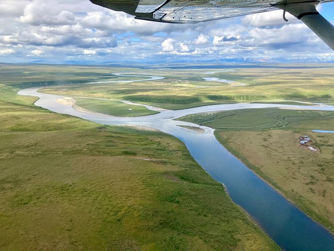 The Noatak River flows and forks with distant mountains.