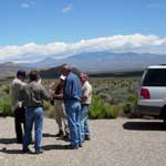 A group of people stand together on a road under clear skies in southern California