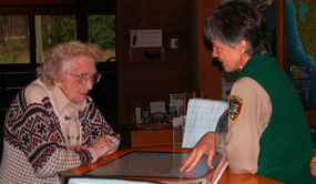 uniformed female volunteer talking with female visitor at information desk