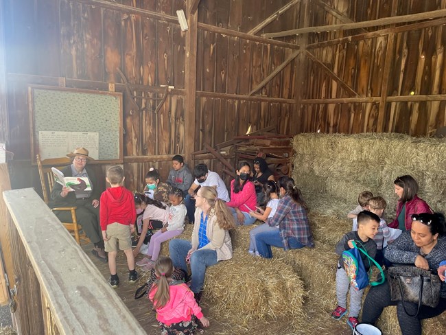 A Park Ranger reads to children in the barn
