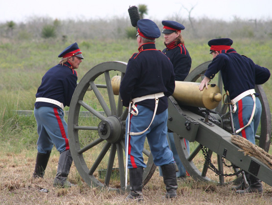 Living historians load a replica cannon.
