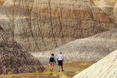 Hikers on the Blue Mesa Trail among colorfully banded badlands