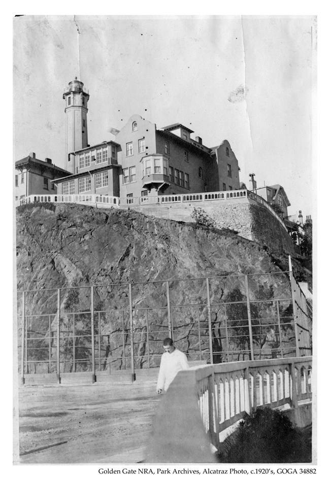 Alcatraz photo c1920s prisoner in all white walking on parade ground below comandants house and light house