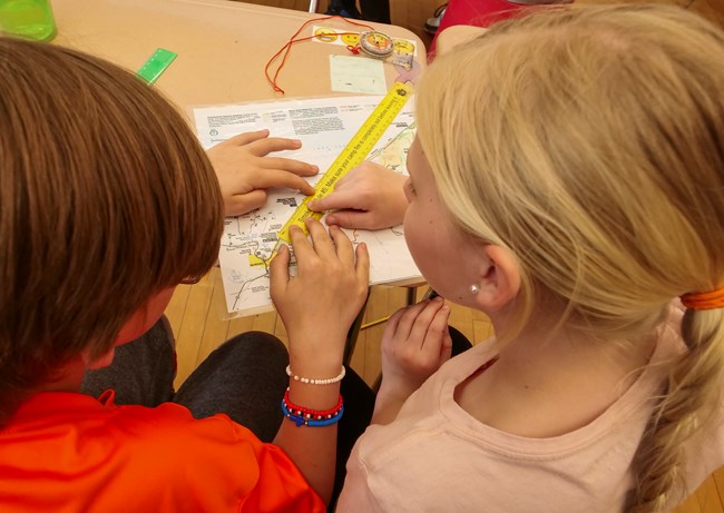 Two students work with a map and ruler