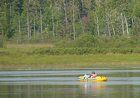 An NPS employee testing for water quality while in an inflatable boat on Little Chapel Lake.