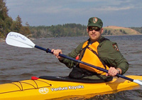 Park Ranger on kayak patrol overlooking the Grand Sable Dunes.