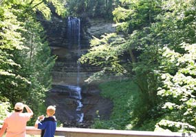 Visitors on a lookout view Munising Falls as the sun shines through on the trees.