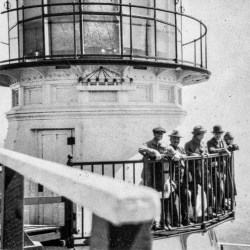 Black and white photo of men standing on lighthouse balcony