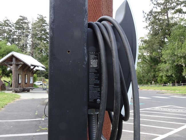 A small, inconspicuous QR code on the side of a black and white electric vehicle charging station.