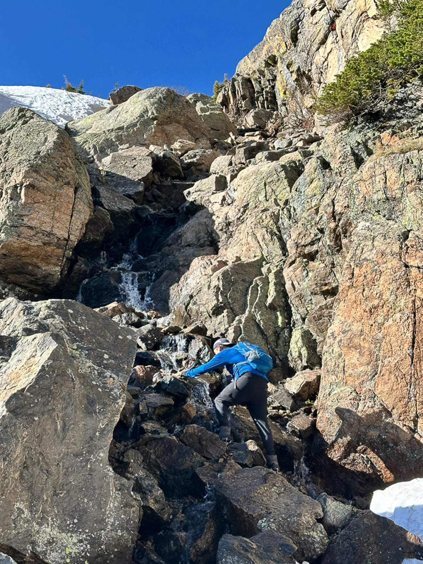 A hiker is beginning to ascend up the gully next to Timberline Falls