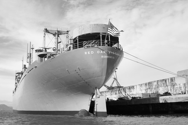 A large ship is anchored next to a concrete dock.