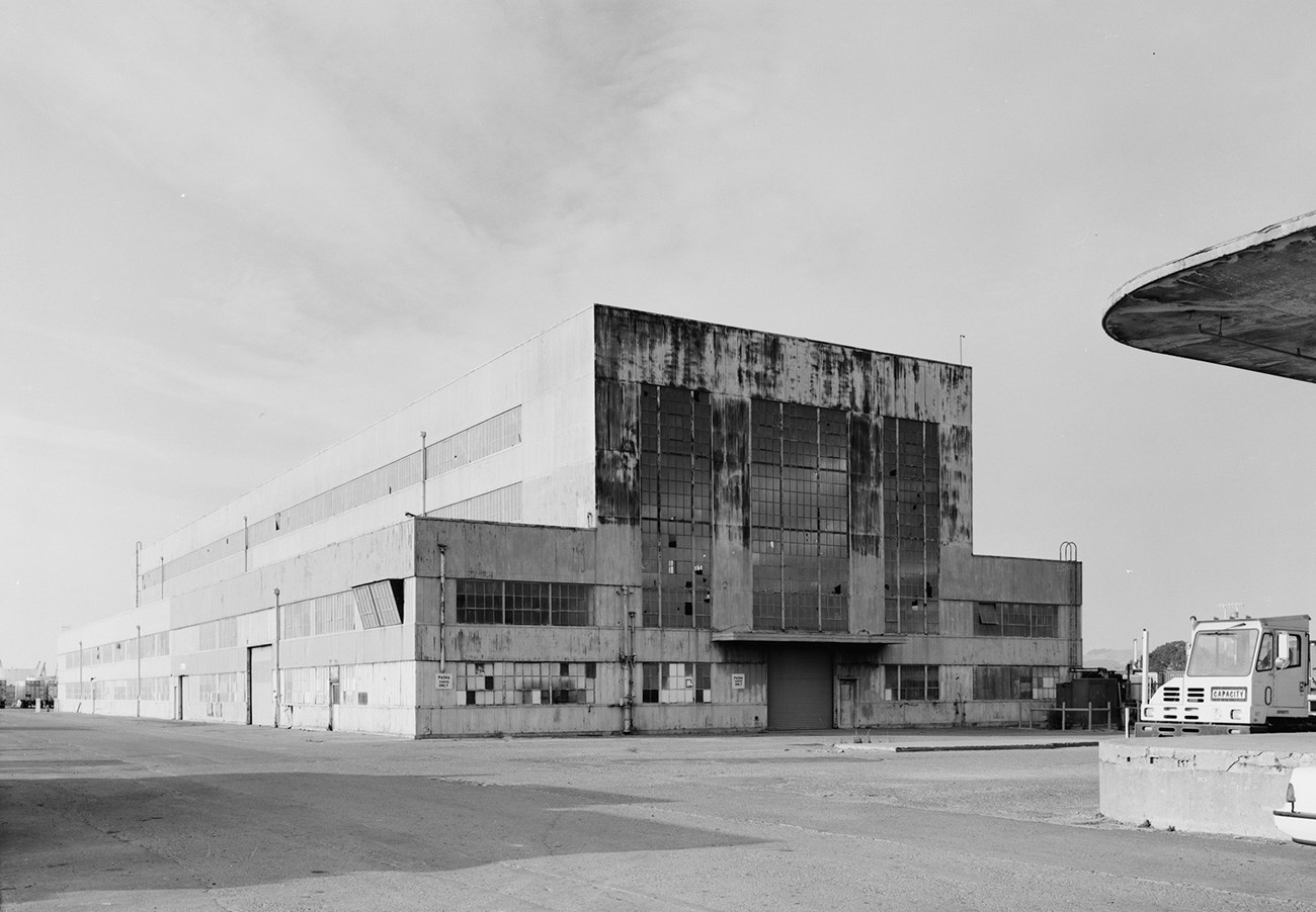 Historic photo of large weathered industrial warehouse building.