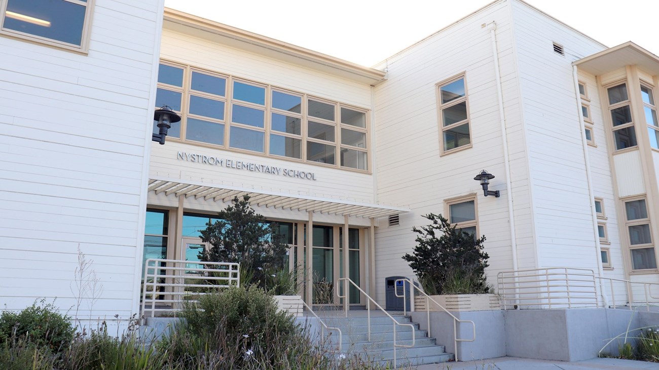 Entry area of a two-story school building with steps and windows.