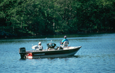 Three men in a red fishing boat rleax and fish