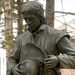 Bronze statue portrays a French man in mourning, holding his hat.