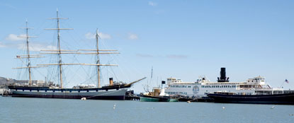 A view across the Aquatic Park lagoon of Hyde Street Pier and the historic ships.