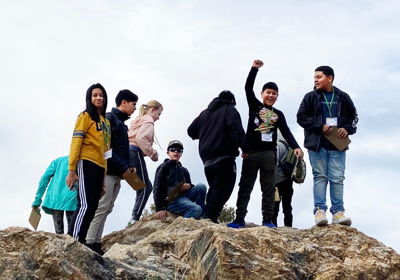 group of kids atop a rocky outcrop, one with fist raised up in victory pose