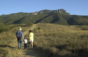 Mother, Father, and Child walk on a trail toward Boney Mountain.