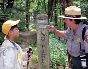 A ranger shows a young hiker how to read the information on a stone trailmarker during a Ranger Program. A ranger shows a young hiker how to read the information on a stone trailmarker during a Ranger Program.