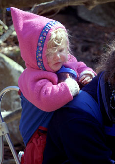 A toddler hitches a ride on her mother's back. A toddler hitches a ride on her mother's back.