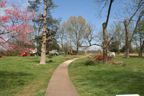 People cutting and chipping fallen trees in front of a monument.