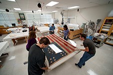 Six people repairing an American flag from the civil war