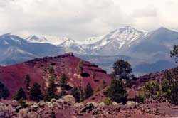 Cinder and lava formations, with snow-covered peaks in background