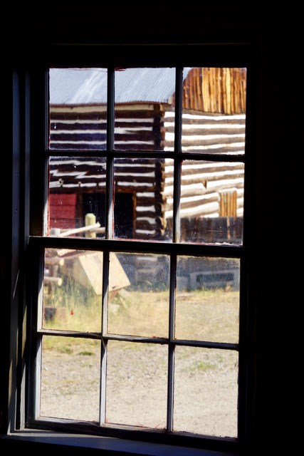 Log draft horse barn through the window pane of the bunkhouse.