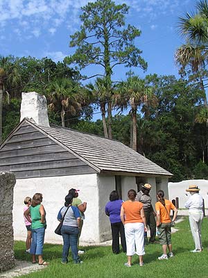 Teachers standing outside of a rehabilitated slave cabin during ranger-guided tour of site for teacher training.