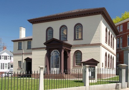 A cream-colored two-story building with arched windows and brown trim.