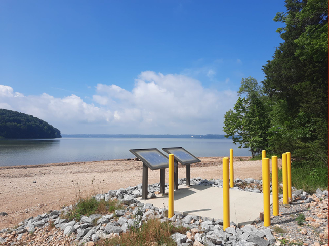 Two concrete pillars sitting next to a lake.