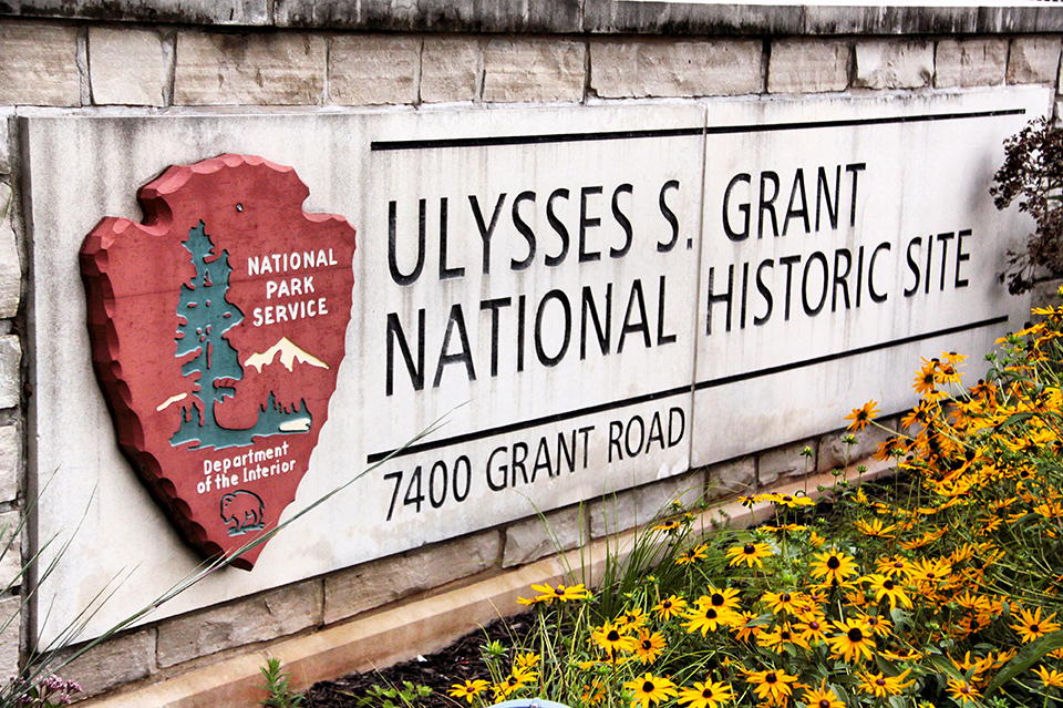 White stone entrance sign for Ulysses S. Grant National Historic Site with yellow flowers