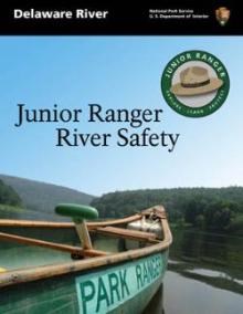 Cover of booklet: photo of a green canoe with "Park Ranger" printed on side. In background are hills with "Junior Ranger River Safety" text in the blue sky. In upper corner is the circular Junior Ranger logo with a green outline and park ranger hat.