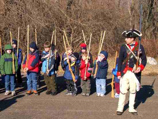 Children learning a musket drill from a continental soldier during the Join the Army Junior Ranger program.