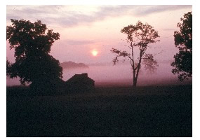 Small wooden hut silhouetted by the rising sun.