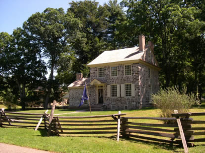 Washington's Headquarters, an 18th century, two story stone building shaded by summer foliage.