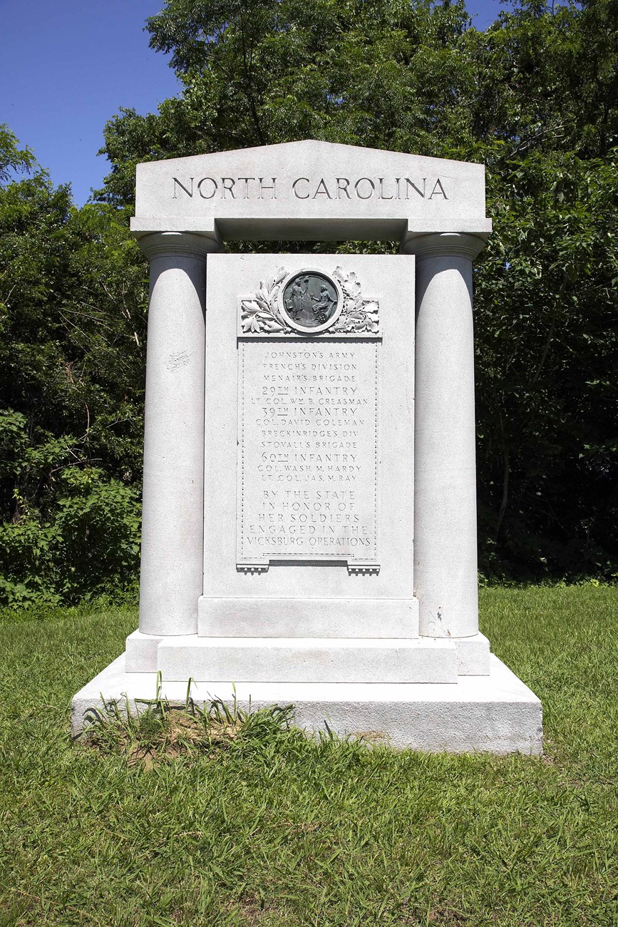 A granite tall slab with a inscription and state seal of North Carolina