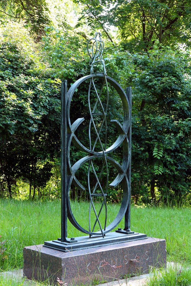 Three green circles sit atop a small platform with an abstract sculpture of an eagle perched at the top.
