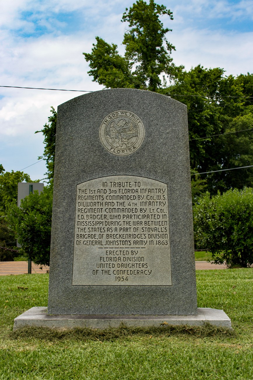 A granite monolith with a polished surface. The Florida State seal is at the top, below it reads a short inscription