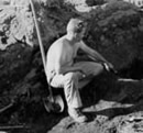 Worker sitting in hole of archeological excavation.