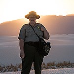 A ranger stands silhouetted by sunset.