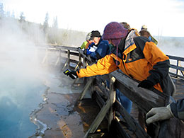 A group on the boardwalk overlooking a hot spring.