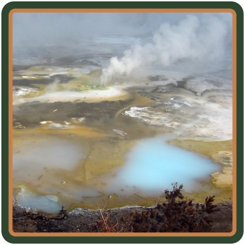 Steam rises from a hot spring that ranges from blue and yellow to milky white.