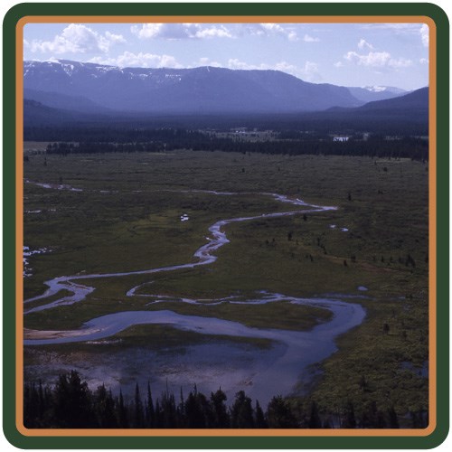 The Yellowstone River meanders through a wide-open valley with mountains in the background.