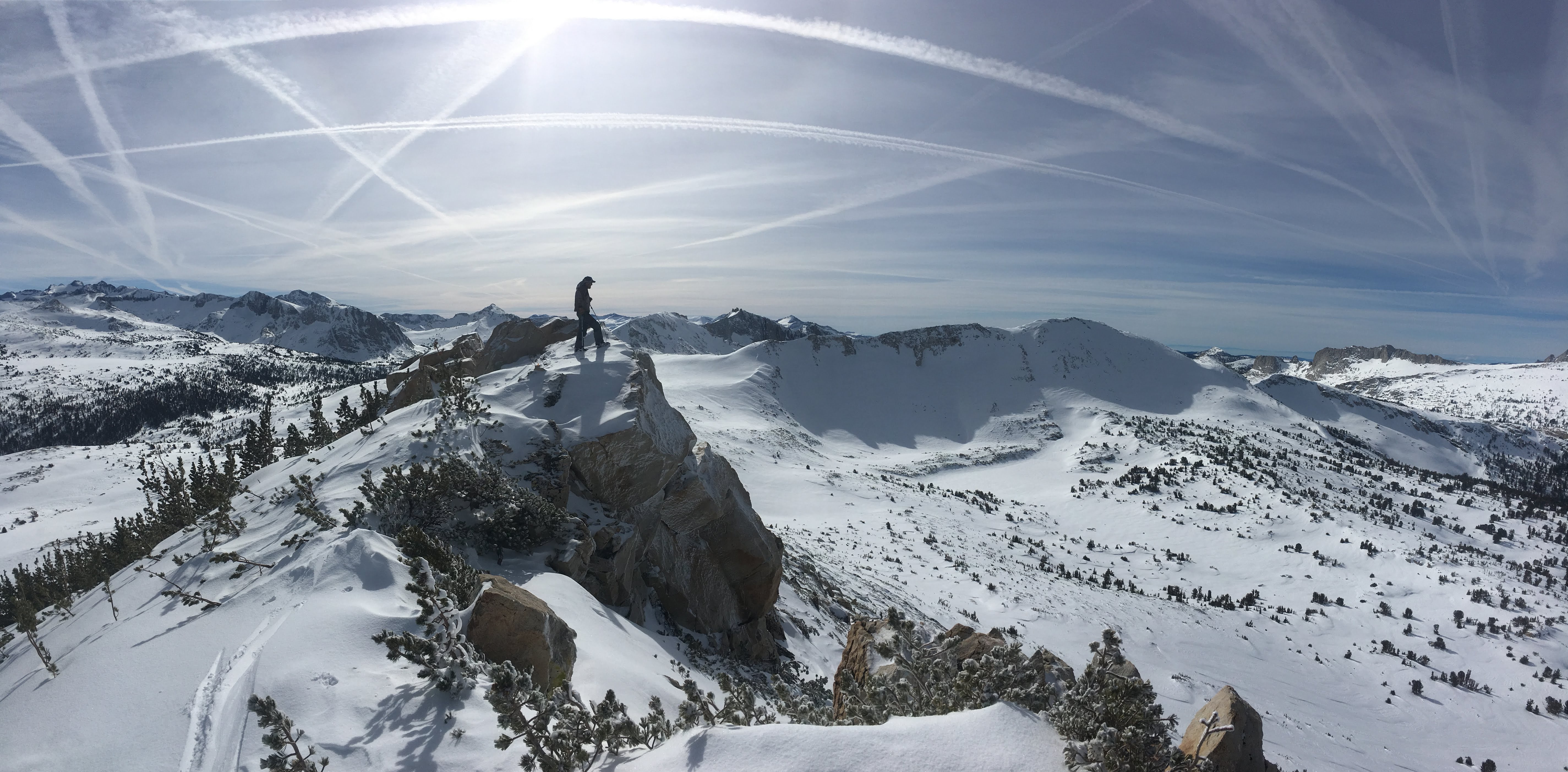 Single person stands on top of windswept snowy ridge