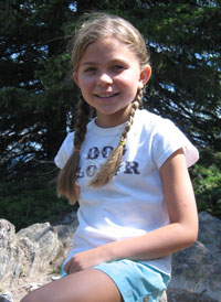 Little girl sits on a rock in park